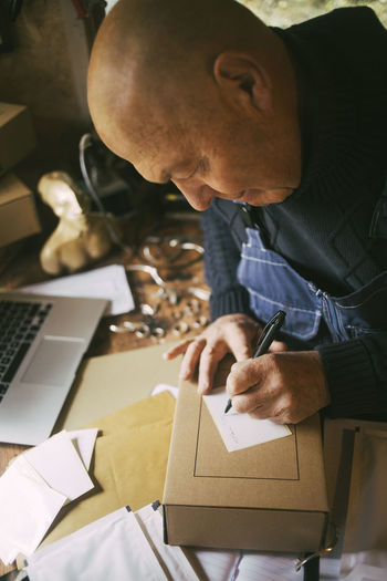 Male entrepreneur writing on label in workshop