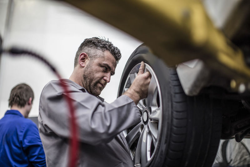 Car mechanic in a workshop changing tire