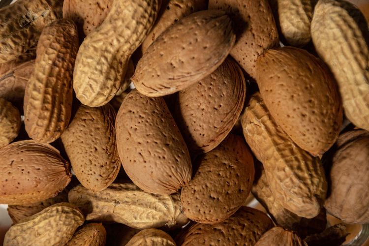 Almonds in shell and peanuts . dry food background details.