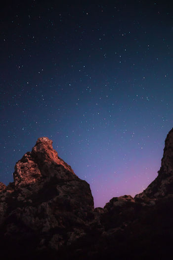 Low angle view of rock formation against sky at night