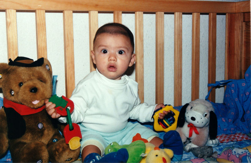 Portrait of cute baby boy sitting on toy at home