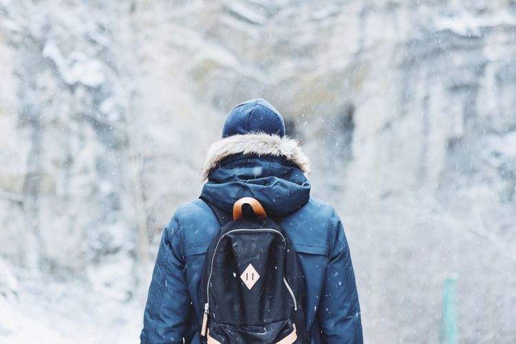 Rear view of person with backpack during snowfall