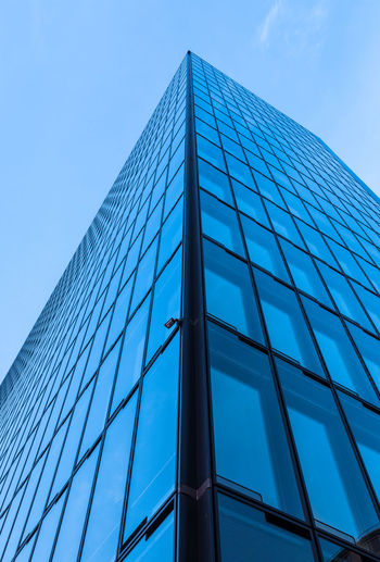 Low angle view of glass building against blue sky