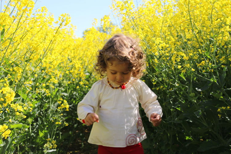 Full length of girl standing on yellow flowering plants
