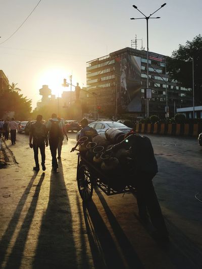 People riding motorcycle on city street during sunset