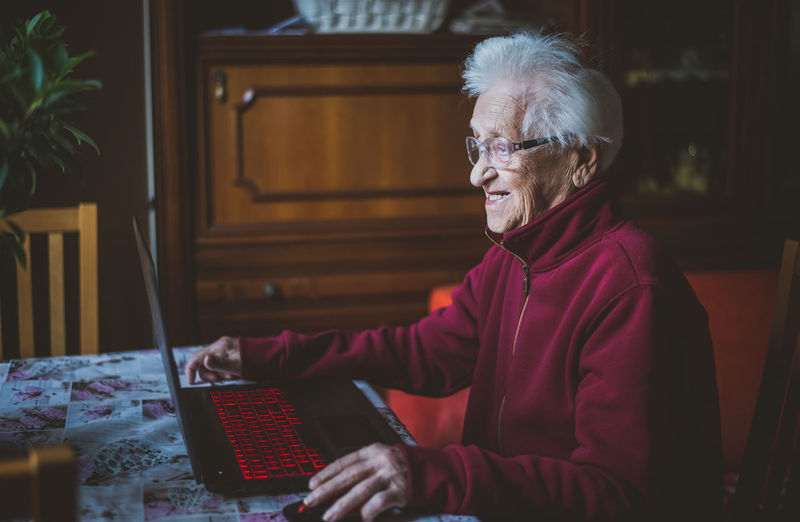 Smiling senior woman using laptop while sitting at home