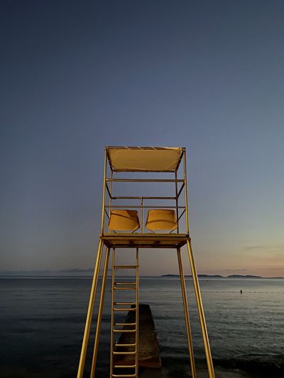 Lifeguard hut by sea against clear sky
