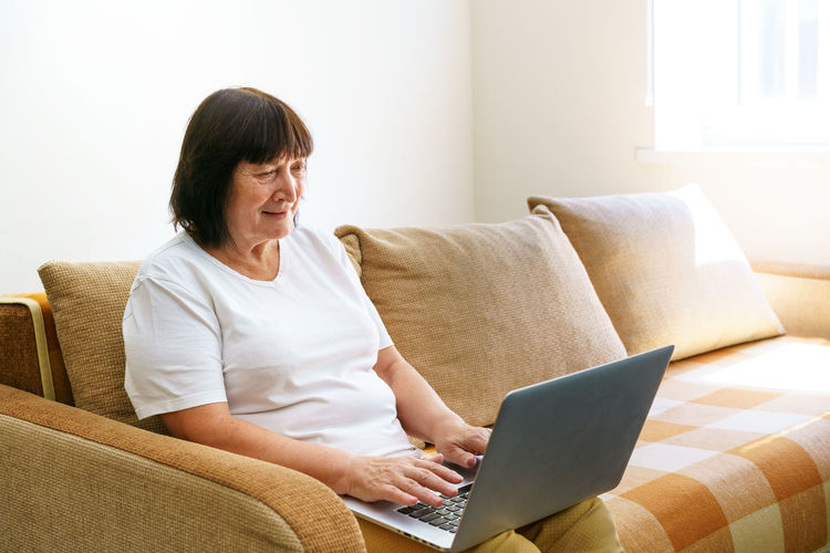 Elderly mature woman using wireless laptop apps