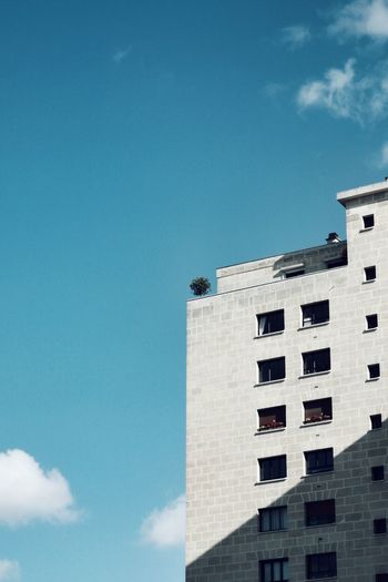 LOW ANGLE VIEW OF OFFICE BUILDING AGAINST BLUE SKY