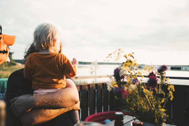 Father embracing daughter at table in holiday villa against sky