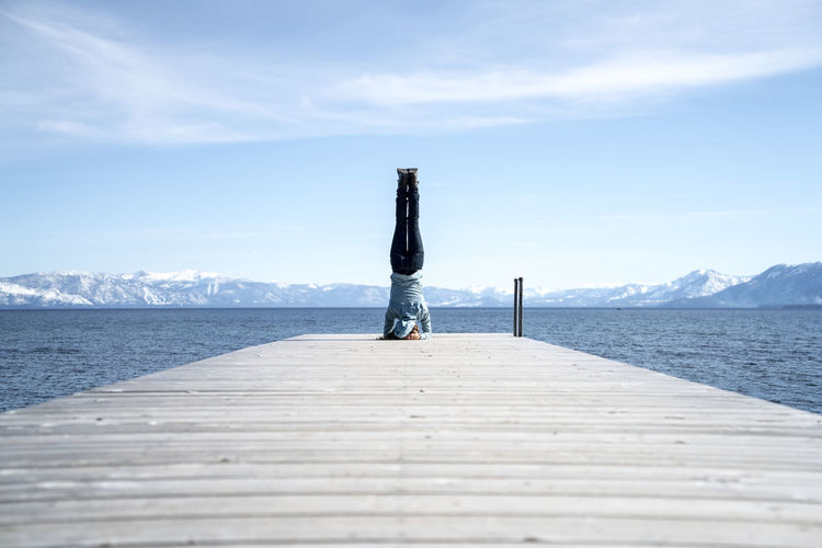 Woman does a headstand at the end of a pier in south lake tahoe, ca