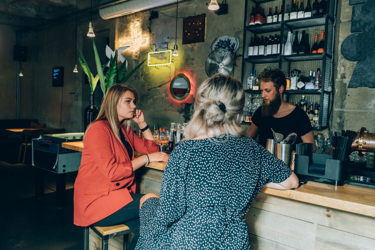 Two girlfriends and bartender in a cocktail bar.