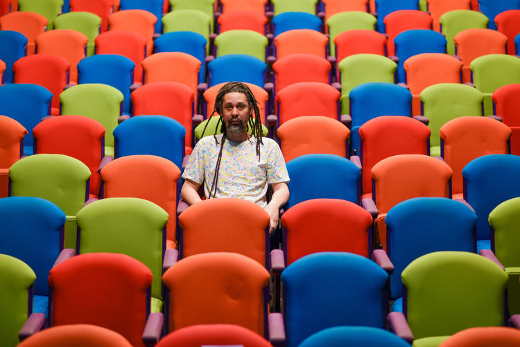 Colorful chairs with one person sitting alone in theatre 
