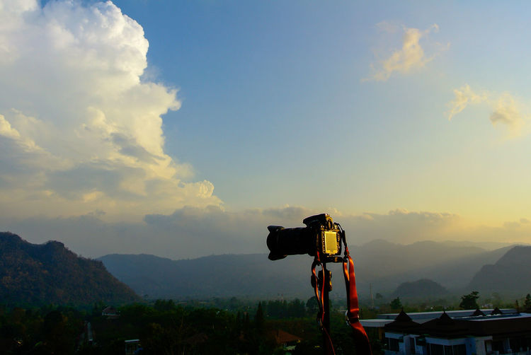 Camera and tripod on high roof , mountains and blue sky clouds after the sunset as background.