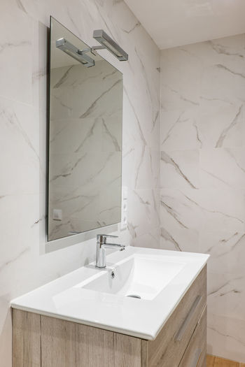 Simple and modern bathroom with marble tiles, sink and mirror