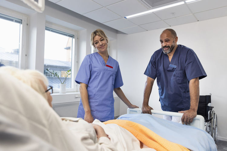 Nurses talking to patient on hospital bed