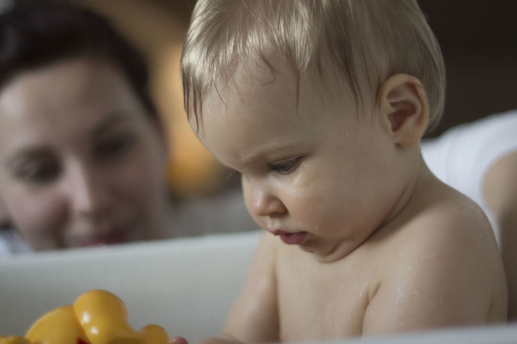 Close-up of cute shirtless baby boy playing with rubber duck