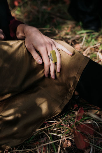 Cropped image of woman wearing ring while sitting on field