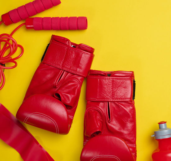 Red leather boxing gloves, water bottle. sports equipment on a yellow background