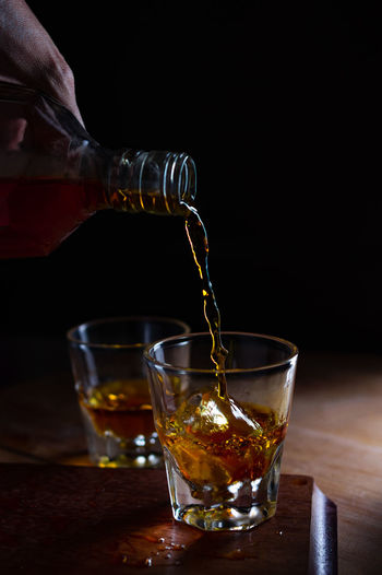 Close-up of pouring whiskey to the glass of ice 