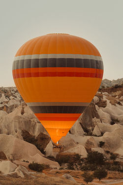 Hot air balloon flying over rocks against clear sky