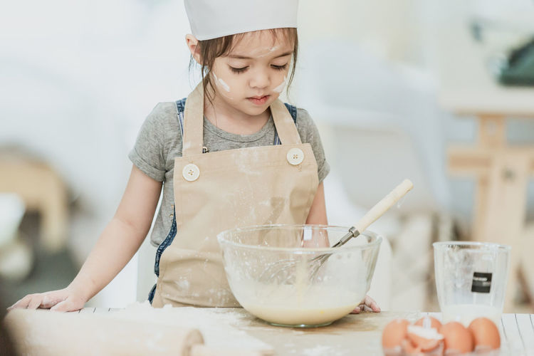 Portrait of girl with ice cream in bowl on table