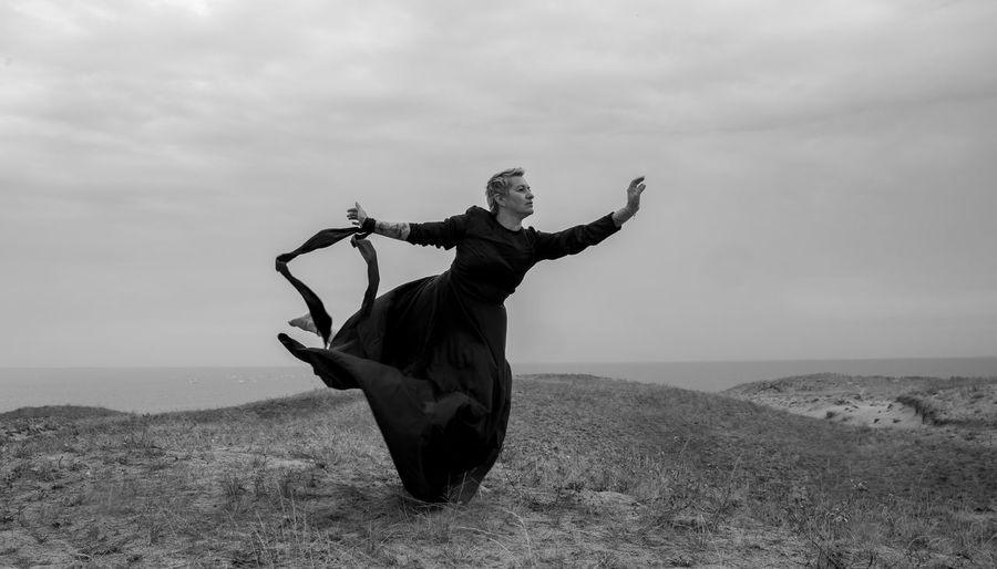 Full length of woman dancing on hill against sky
