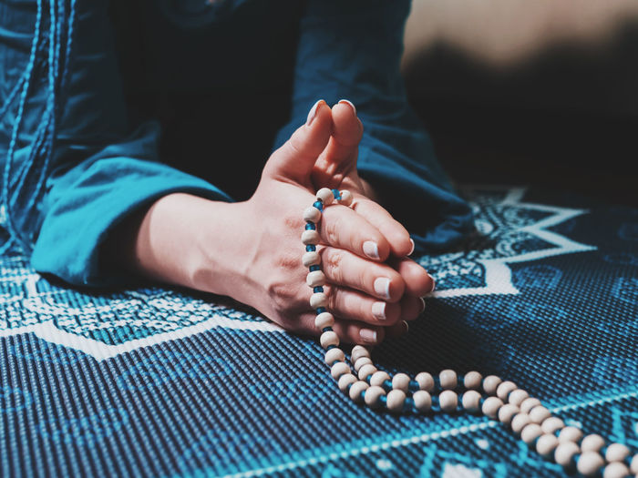 Midsection of woman praying on carpet at home