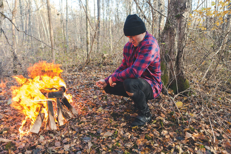 Man roasting food in campfire at forest