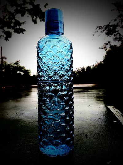 Close-up of wet glass bottle on lake