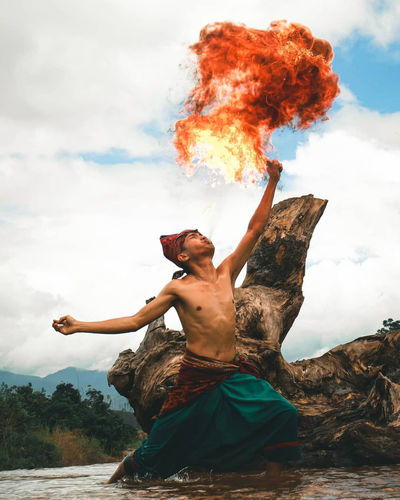 Full length of shirtless man dancing against sky