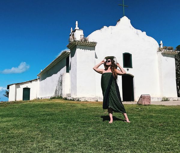 Full length of woman standing on field against church