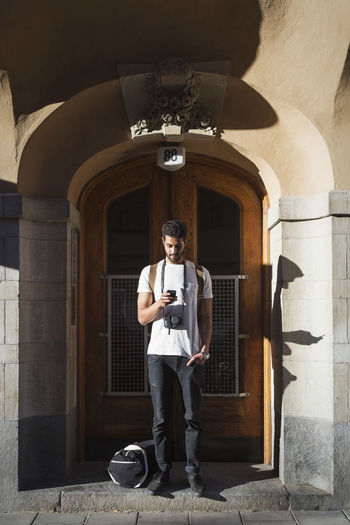 Tourist using smart phone while standing at doorway