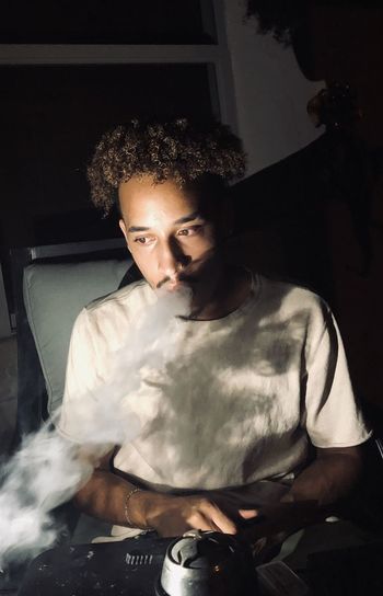Young man smoking hookah at home