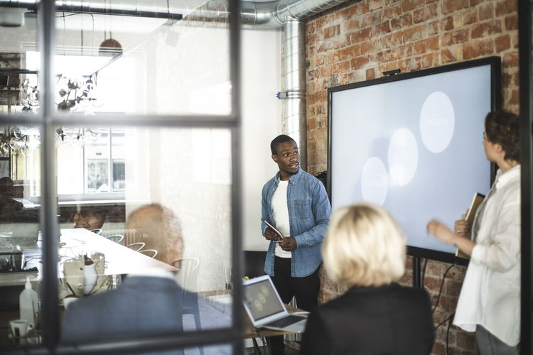 Businessman giving presentation to male and female investors in office