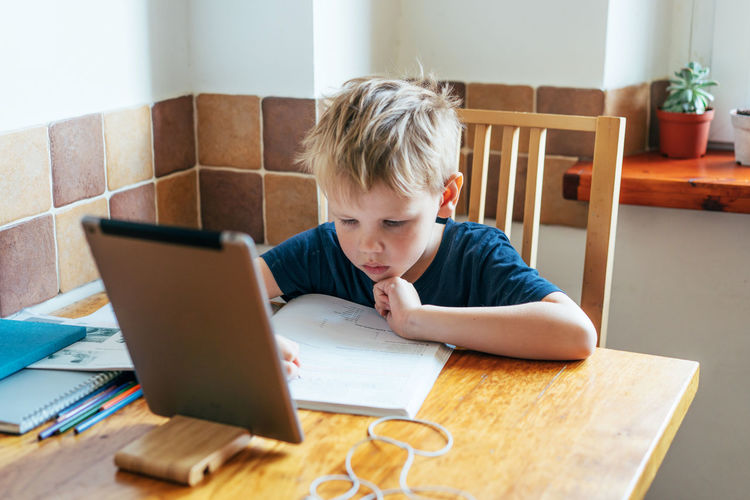 Boy studying by using digital tablet at home