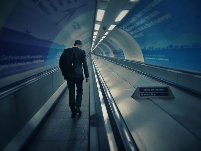 Man walking on escalator at subway station