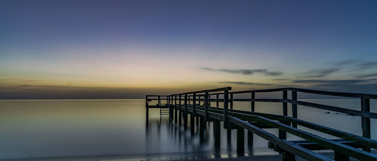 Pier over sea against sky during sunset