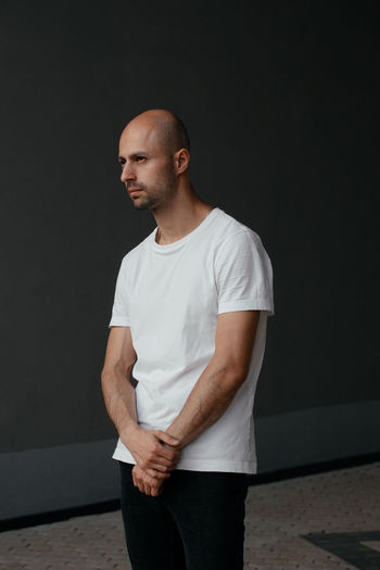 Image of a handsome bald man in a white t-shirt on a gray background