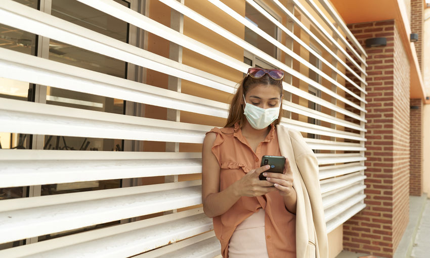 Young business woman wear face mask protect of coronavirus standing at modern office. covid-19