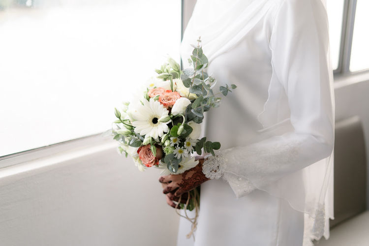 Midsection of muslim bride holding bouquet