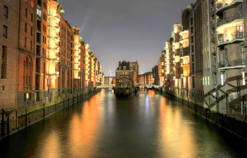 Canal amidst illuminated buildings in speicherstadt at night