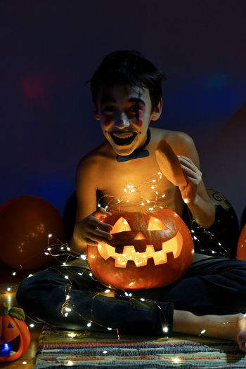 Close-up of a boy with pumpkin at night during halloween