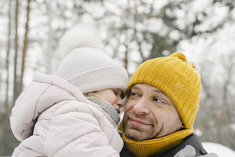Man in yellow knit hat with daughter in winter