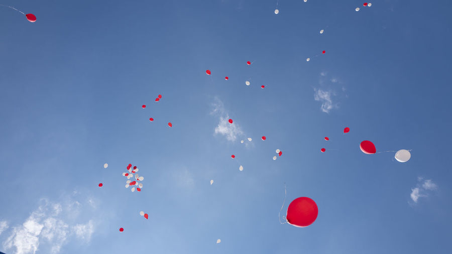 Low angle view of balloons flying against blue sky