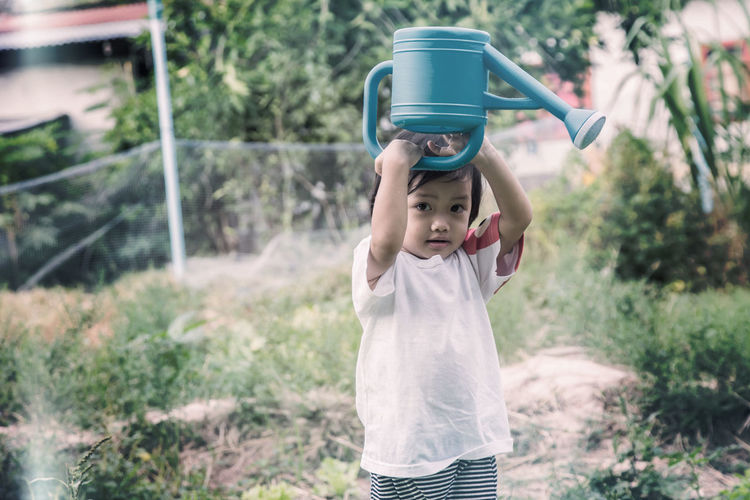 Portrait of girl with watering can outdoors