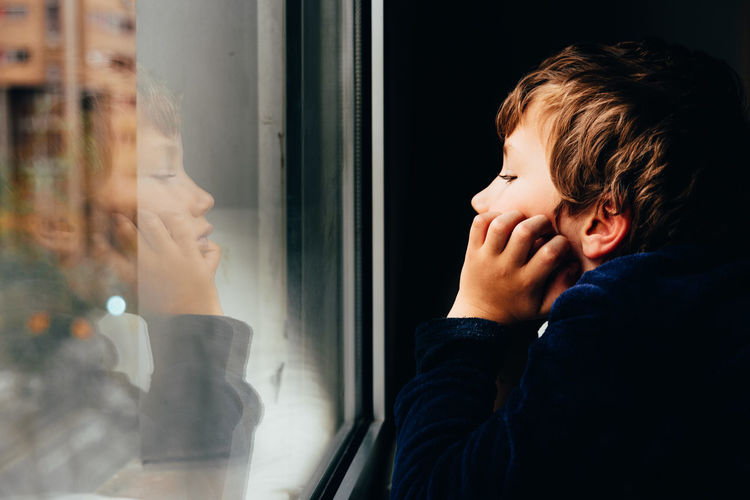 Portrait of boy looking through window