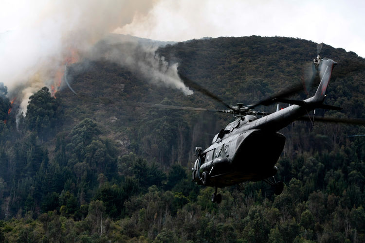 Helicopter flying against fire on mountain