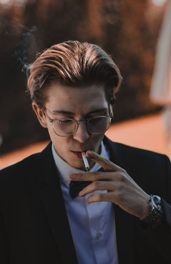 Close-up of young man with glasses smoking cigarette