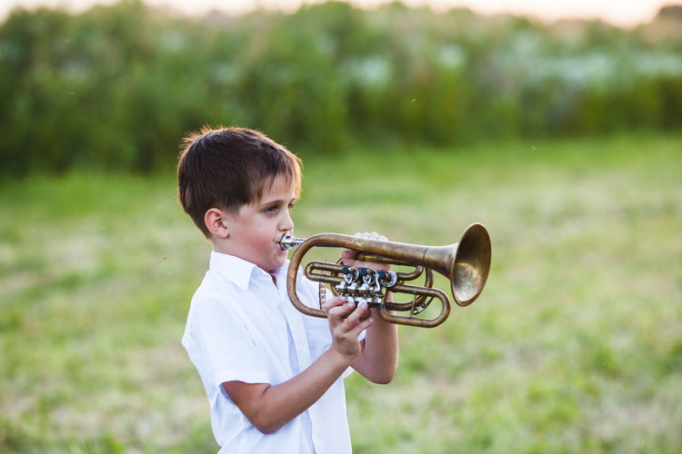 Smiling boy playing trumpet outdoors
